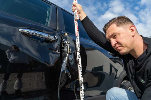 Kfz-Sachverständiger Alexander Fertig vermisst einen Fahrzeugschaden an einem schwarzen Auto